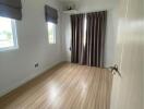 Empty bedroom with wooden flooring and large windows