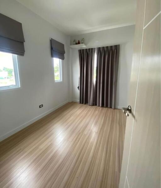 Empty bedroom with wooden flooring and large windows