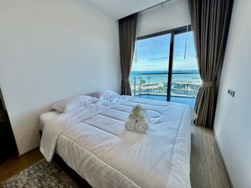 A bedroom with a large window and ocean view