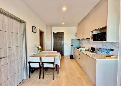 Modern kitchen and dining area with wooden floor, refrigerator, microwave, and dining table