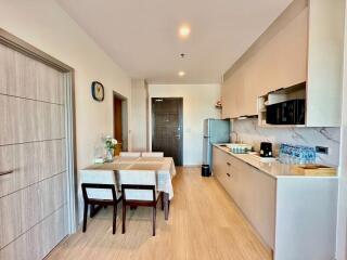 Modern kitchen and dining area with wooden floor, refrigerator, microwave, and dining table