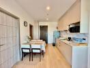 Modern kitchen and dining area with wooden floor, refrigerator, microwave, and dining table