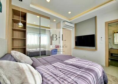 Well-lit modern bedroom with mirror closet and wall-mounted TV