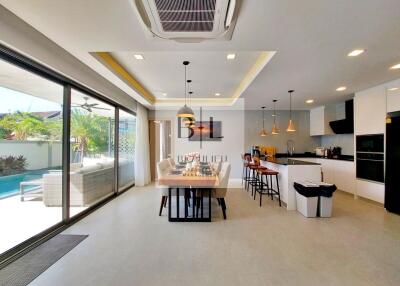 Modern kitchen and dining area with large sliding doors opening to a poolside patio.