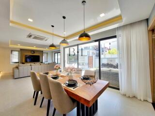 Spacious dining area with a modern setting, adjacent to a living room and large windows leading to a patio