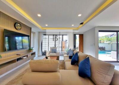 Modern living room with large TV, comfortable sofas, and view of swimming pool