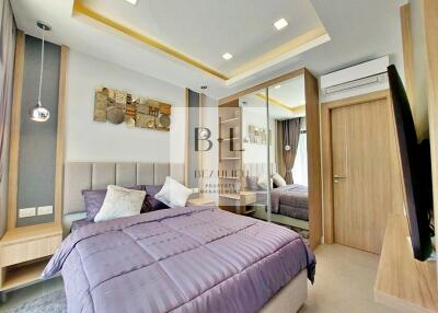 Modern bedroom with purple bedspread, mirrored wardrobe, and wall art