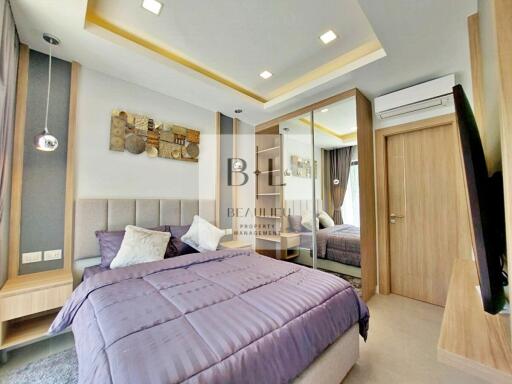 Modern bedroom with purple bedspread, mirrored wardrobe, and wall art