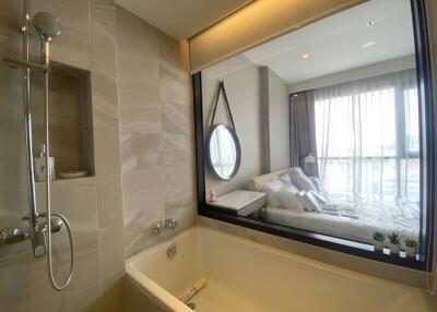 Modern bathroom with bathtub and view of bedroom through large window