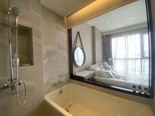 Modern bathroom with bathtub and view of bedroom through large window