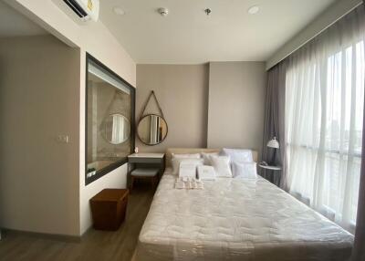 Modern bedroom with large window, double bed, and vanity area