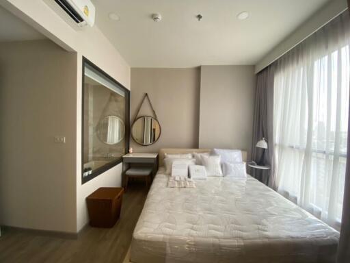 Modern bedroom with large window, double bed, and vanity area