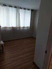 Empty room with wooden floor and curtain-covered window
