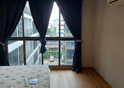 Bedroom with large window and urban view