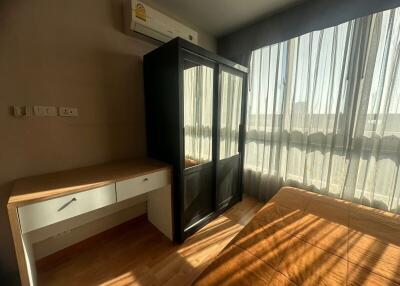 Bedroom with wooden furniture, large window, and air conditioning unit