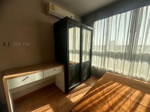 Bedroom with wooden furniture, large window, and air conditioning unit