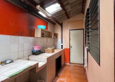 Narrow kitchen with orange tiles and exposed ceiling