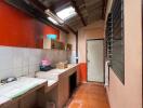 Narrow kitchen with orange tiles and exposed ceiling