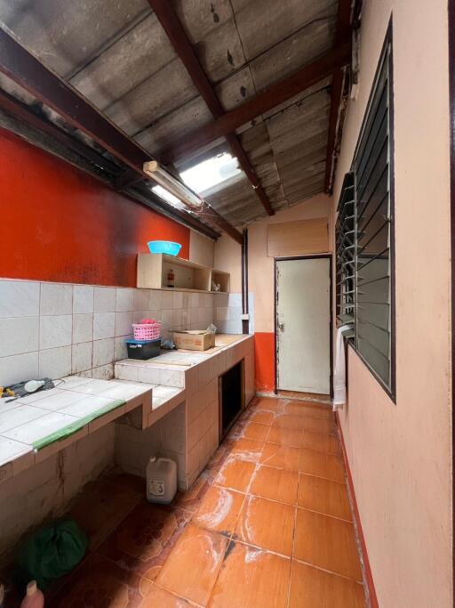 Narrow kitchen with orange tiles and exposed ceiling