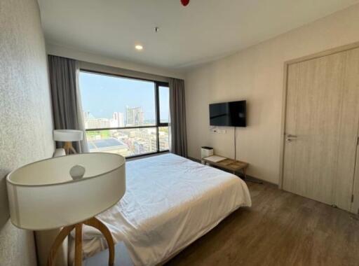 Bedroom with a view, featuring a bed, wall-mounted TV, a nightstand, and a large window