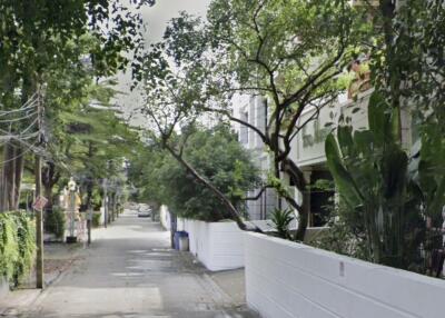Street view of a residential area with white fences and greenery