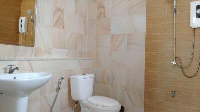 Modern bathroom with tiled walls, a toilet, sink, and shower