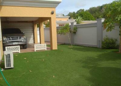 Residential backyard with a carport and artificial grass lawn