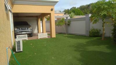 Residential backyard with a carport and artificial grass lawn