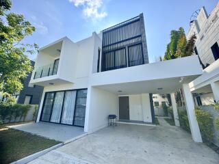 Modern two-story house exterior with carport and greenery