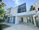 Modern two-story house exterior with carport and greenery