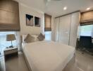 Modern bedroom with double bed, white wardrobe, bedside table with lamp, desk, and chair.