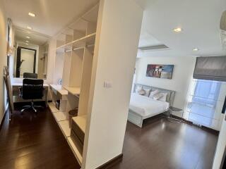 A spacious bedroom with a connected office space and ample storage