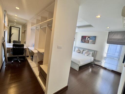 A spacious bedroom with a connected office space and ample storage