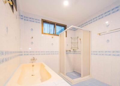 Spacious bathroom with a bathtub, shower, and window