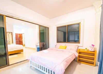 Bright and spacious bedroom with a large bed, side table, and sliding glass doors.