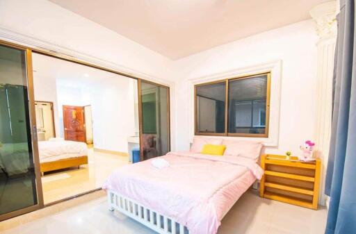 Bright and spacious bedroom with a large bed, side table, and sliding glass doors.