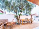 Outdoor seating area with dining table and chairs, tree, and adjacent buildings