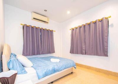 Bedroom with blue bedding, air conditioner, and purple curtains