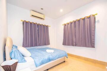 Bedroom with blue bedding, air conditioner, and purple curtains