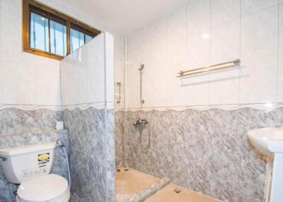 Picture of a bathroom with tiled walls, shower area, toilet, and sink
