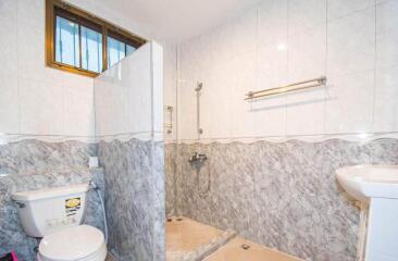 Picture of a bathroom with tiled walls, shower area, toilet, and sink