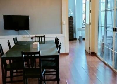 Dining area with wooden floor and wall-mounted TV