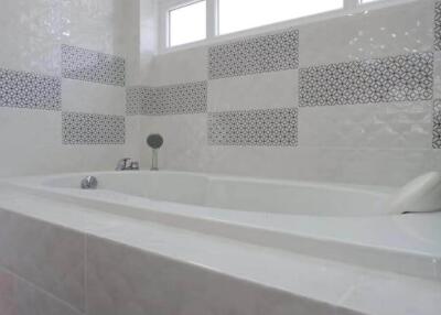Bathroom with tiled bathtub and patterned accent tiles