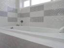 Bathroom with tiled bathtub and patterned accent tiles