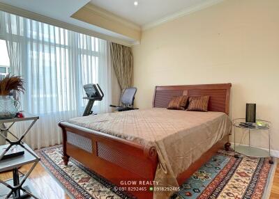 Spacious bedroom with wooden bed, exercise equipment, and large windows