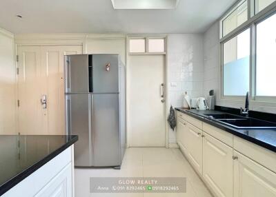 Modern kitchen with sleek countertops, ample storage, and stainless steel fridge