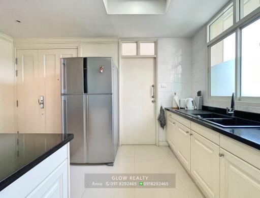 Modern kitchen with sleek countertops, ample storage, and stainless steel fridge