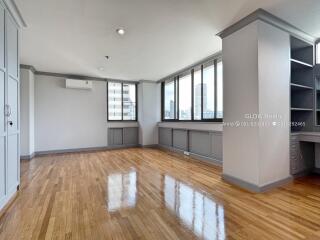 Spacious living area with polished wooden floors, large windows, and built-in desk