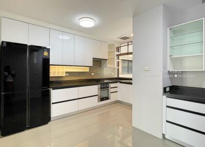 Modern kitchen with white cabinets, black countertops, and black refrigerator