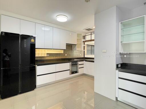 Modern kitchen with white cabinets, black countertops, and black refrigerator